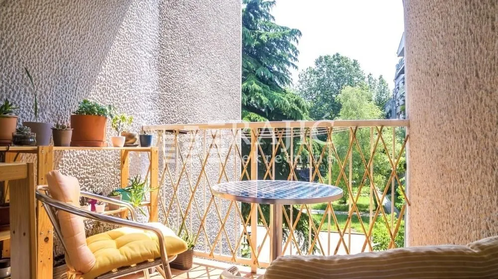 Namešten balkon sa stolom, stolicama i saksijama sa cvećem.
