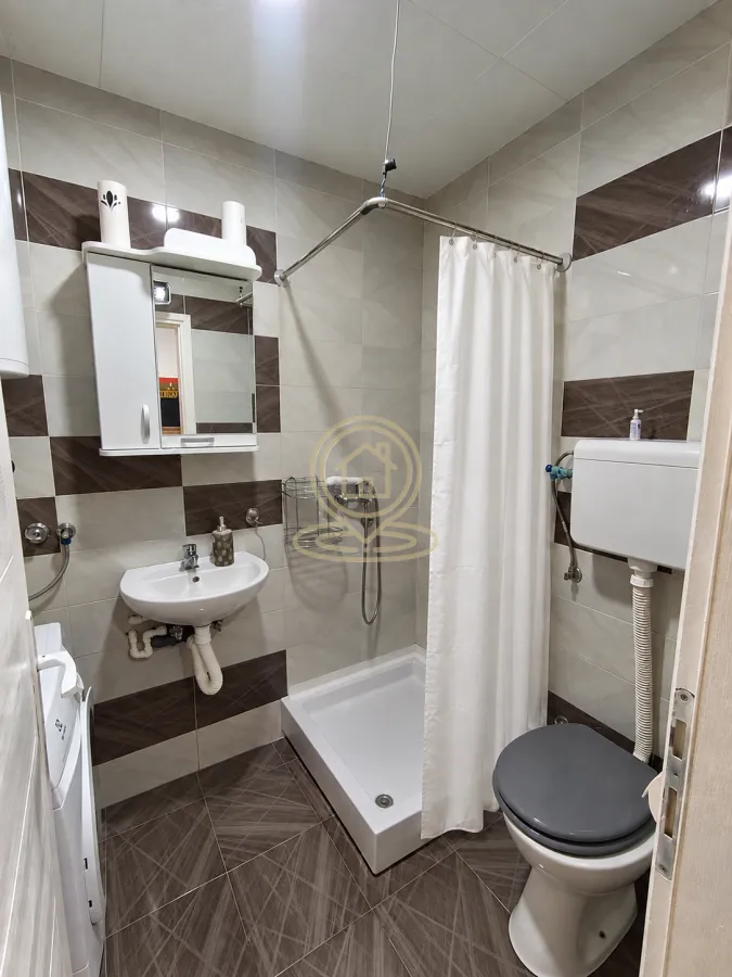 Kompaktno kupatilo sa tuš kabinom, umivaonikom, ogledalom i WC šoljom.