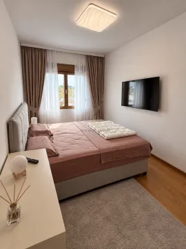 Modern bedroom with a double bed, wall-mounted TV, and window with curtains. - image 9