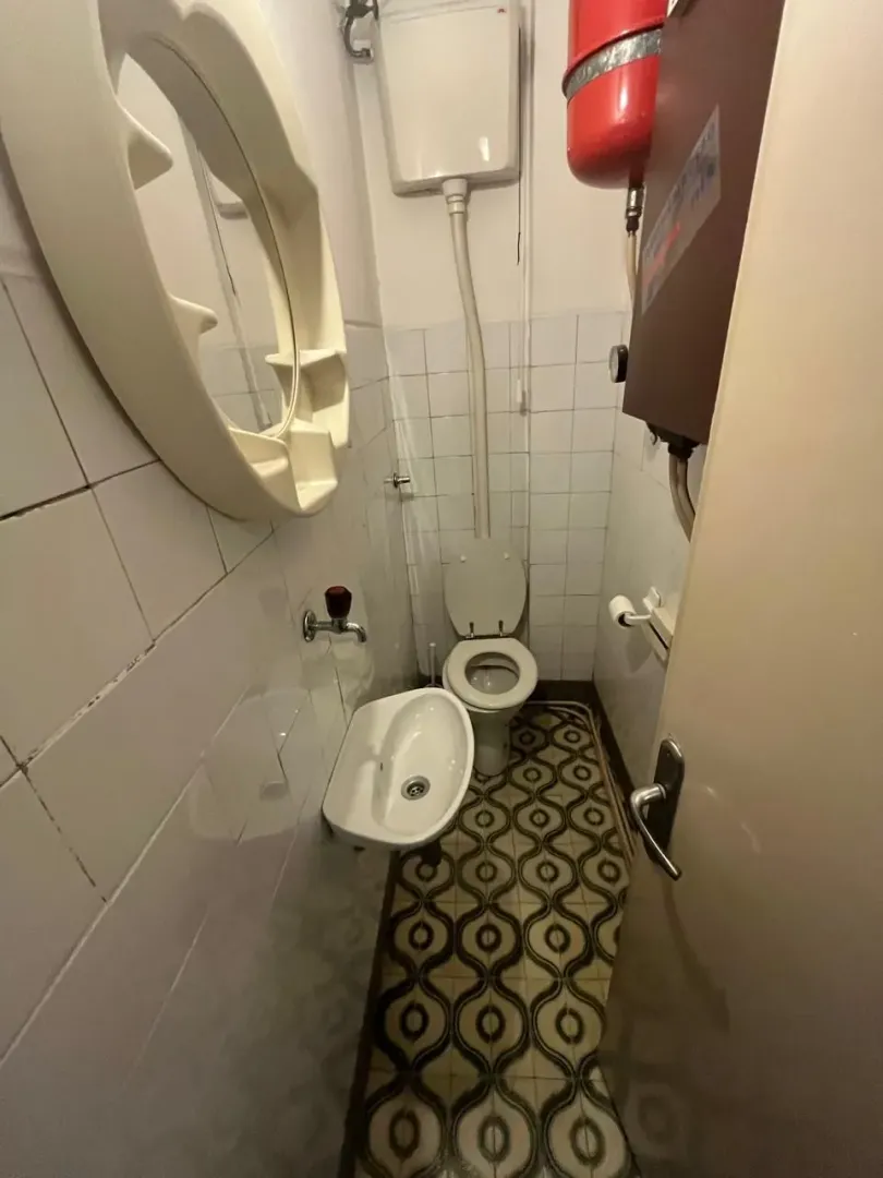 Manje kupatilo sa WC šoljom, umivaonikom i ogledalom.