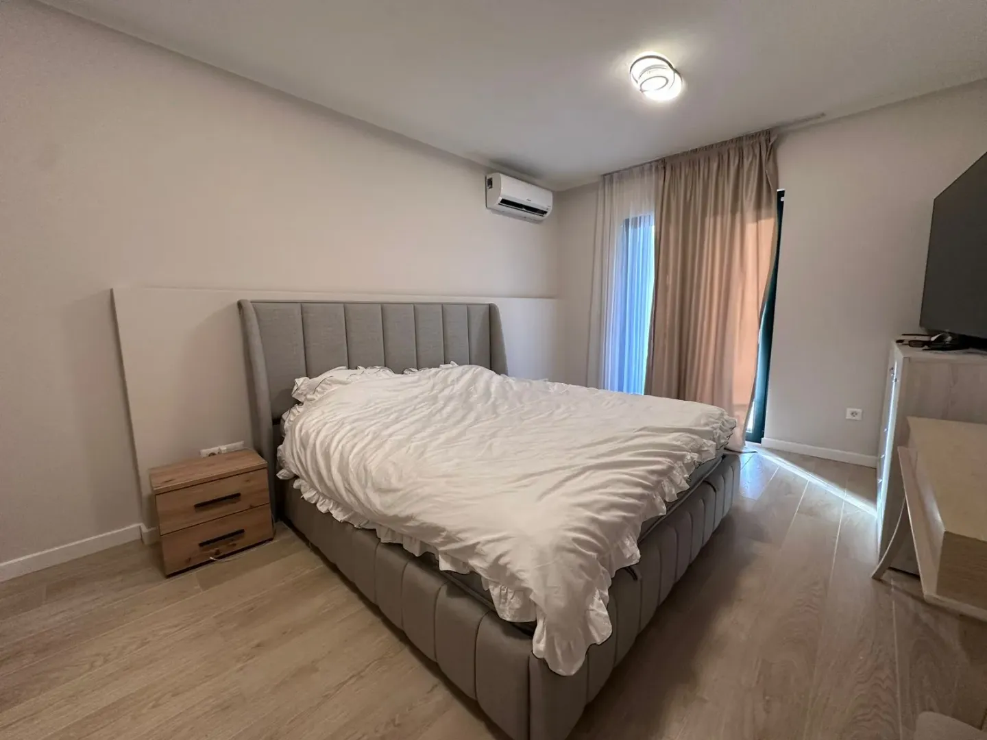 Prostrana spavaća soba sa bračnim krevetom, noćnim stočićem i klima uređajem.