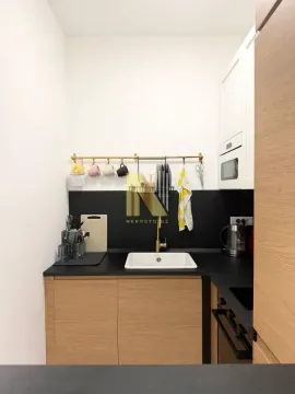 Moderna kuhinja sa belim elementima, drvenim frontama i crnom radnom pločom. - image 8