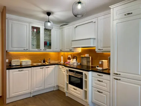 Modern white kitchen with built-in oven and warm lighting. - image 5