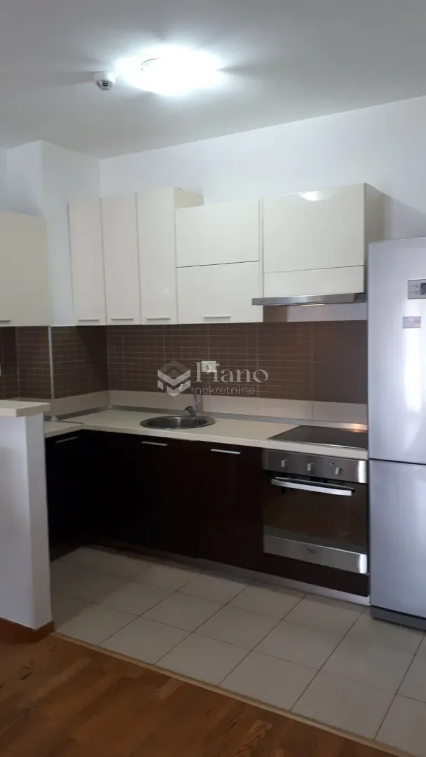 Kitchen equipped with white upper and dark lower cabinets and built-in appliances.