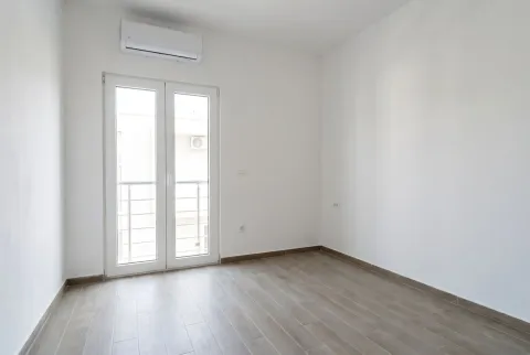 Prazna, svijetla soba sa klima uređajem i balkonskim vratima. - image 12