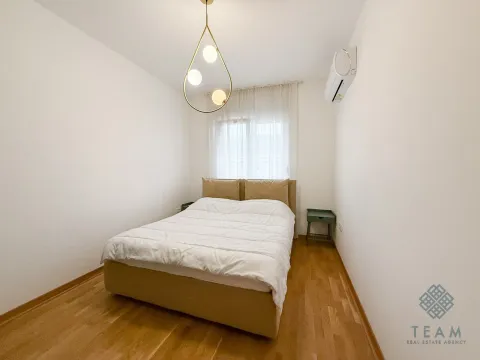 Spavaća soba sa bračnim krevetom, drvenim podom i modernom visećom lampom. - image 7