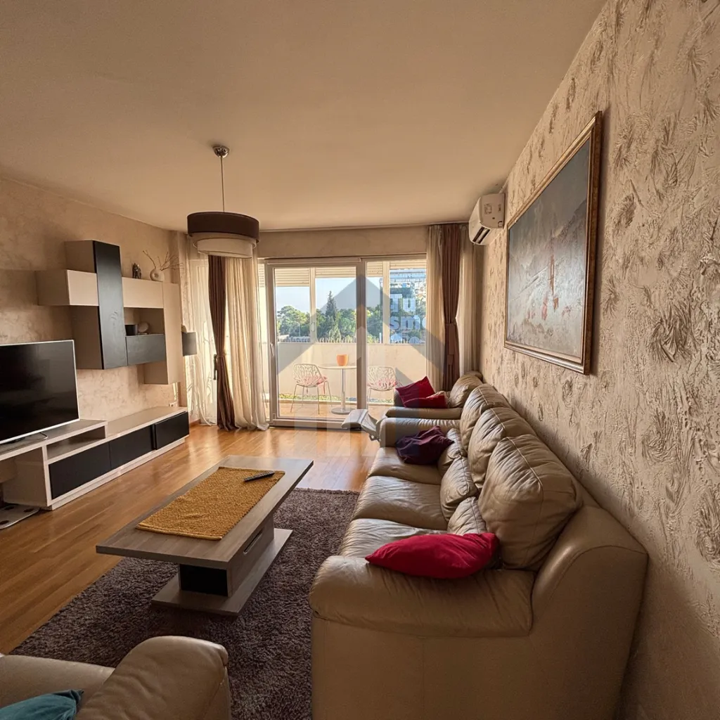 Spacious living room with a sofa set, TV unit, and access to the terrace.