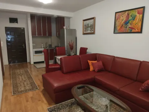 A living room with a large red sectional sofa and a kitchen in the background. - image 5