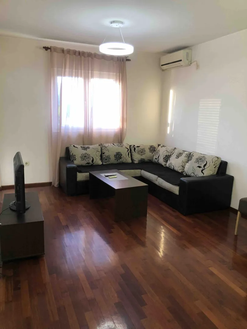 Bright living room with a sectional sofa and wooden flooring.