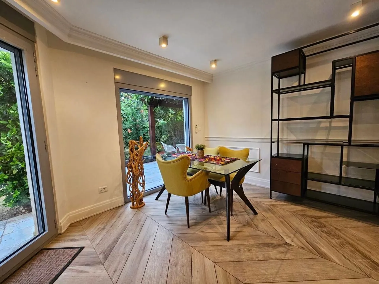 Modern dining room with a table, yellow chairs, and access to the courtyard.