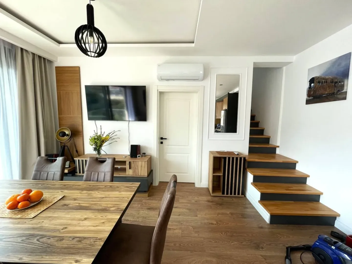 Living room with a dining table and staircase.