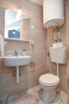 Bathroom equipped with a washbasin, toilet, and water heater. - image 4