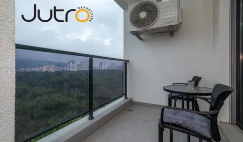 Natkriveni balkon sa garniturom za sedenje i pogledom na zelenilo i grad. - image 8