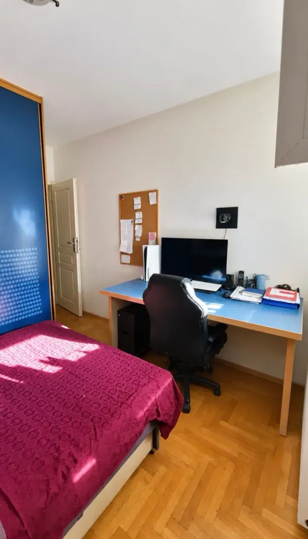 Spavaća soba sa krevetom, radnim stolom i plakarom.