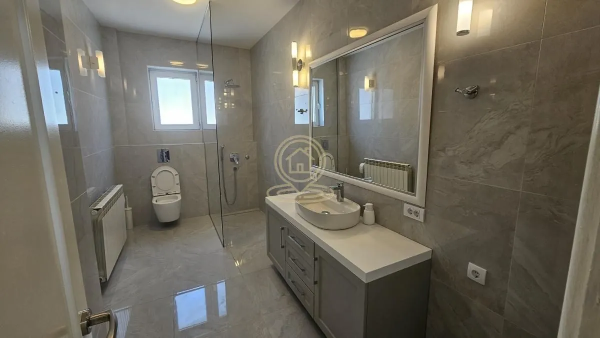 Modernly equipped bathroom with a washbasin, walk-in shower, and ceramic tiles.