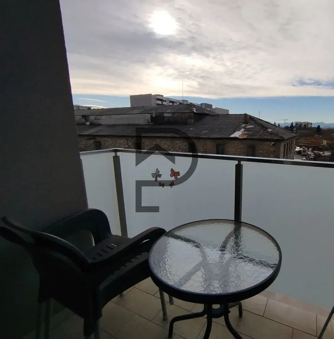 Small balcony with a table, chair, and a view of surrounding buildings.
