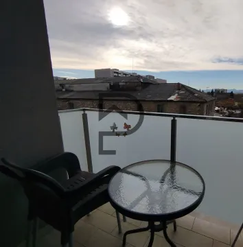 Small balcony with a table, chair, and a view of surrounding buildings. - image 12