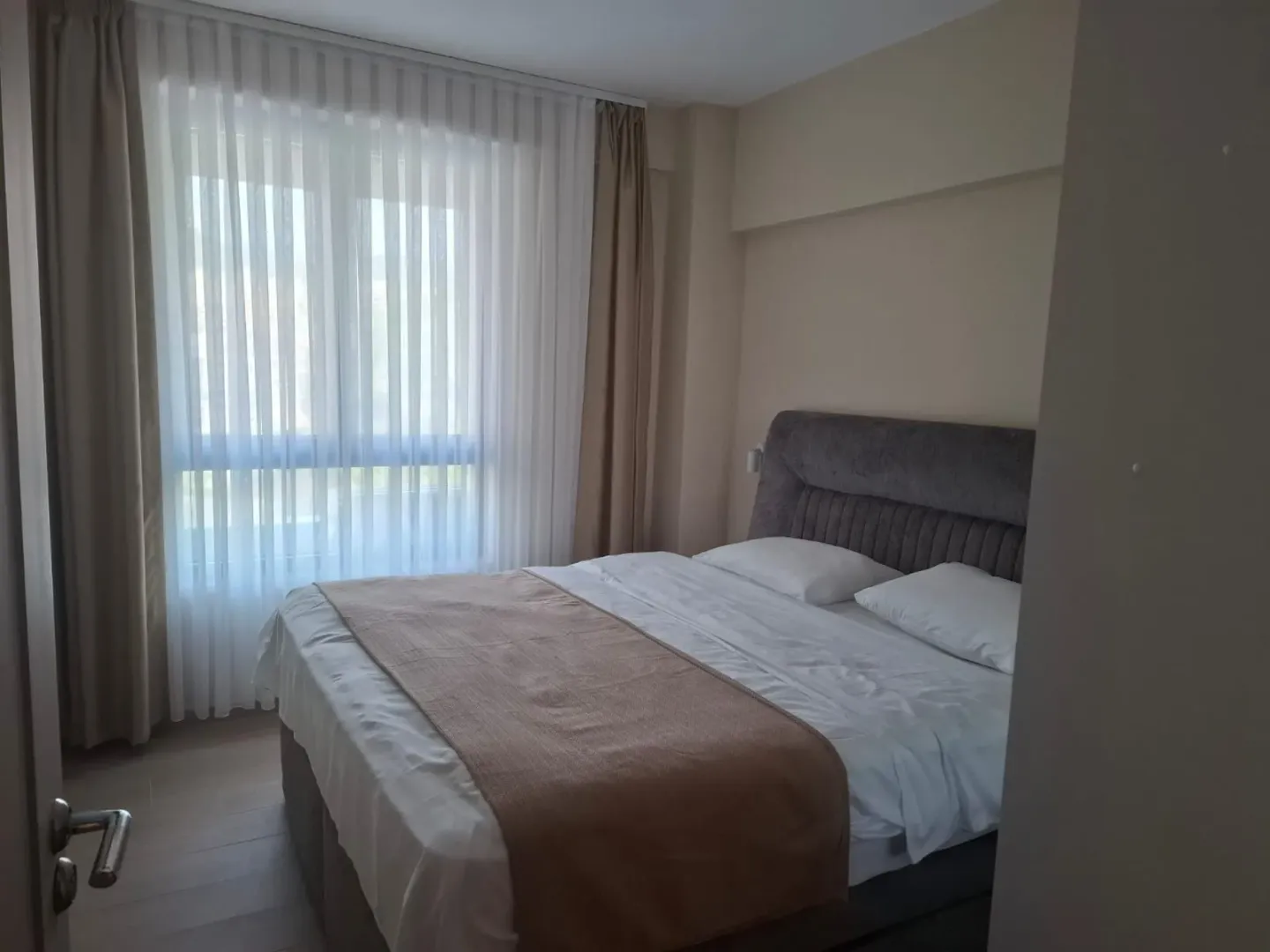 Namještena spavaća soba sa bračnim krevetom i prozorom.