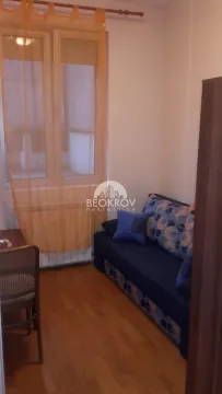 Small bedroom with a sofa bed and a window with an orange curtain. - image 4