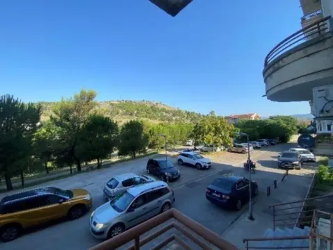 Pogled sa terase na okolno zelenilo i parking ispred zgrade. - image 4