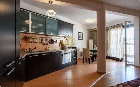 Moderna kuhinja sa tamnim elementima i trpezarijom u pozadini. - image 3