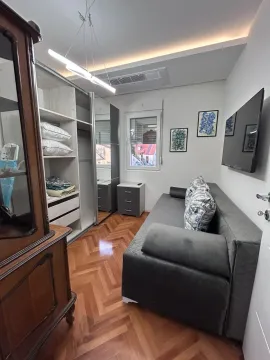 Small bedroom with a sofa, large wardrobe, and wooden parquet flooring. - image 9