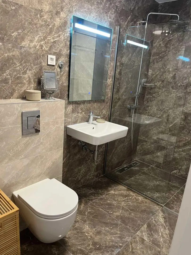 Moderne kupatilo sa tuš kabinom, umivaonikom i wc šoljom.