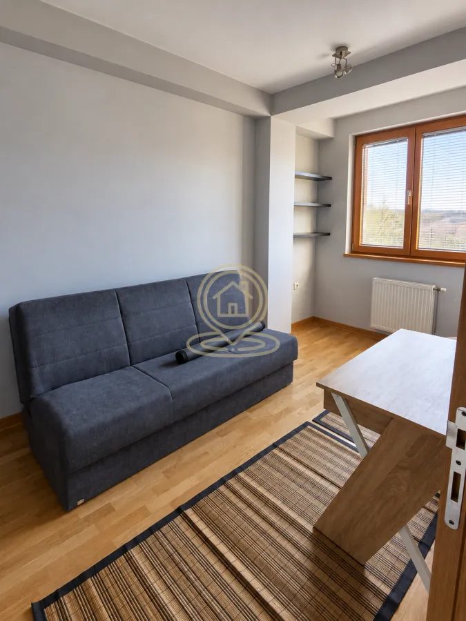 Living room with a grey sofa, desk and window.