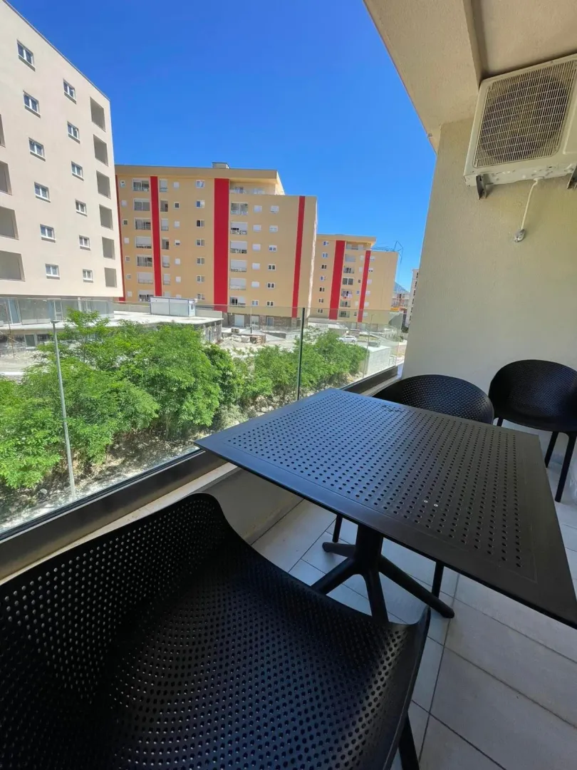 Furnished balcony with seating set and neighborhood view.