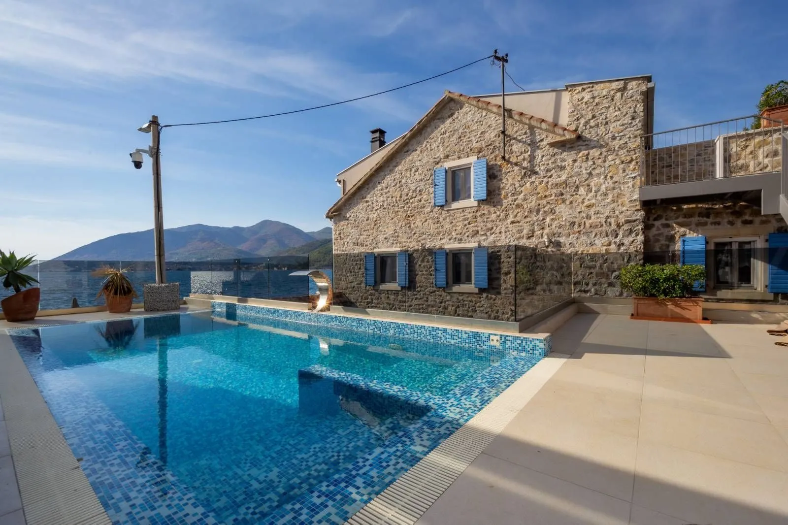 Exterior of a stone house with a swimming pool and sea view.