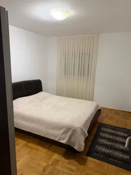 Spavaća soba sa bračnim krevetom, parketom i bijelim zidovima. - image 4