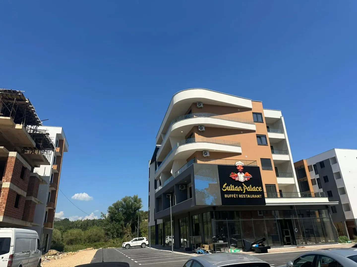 Exterior of a modern multi-family building with commercial space on the ground floor and parking.