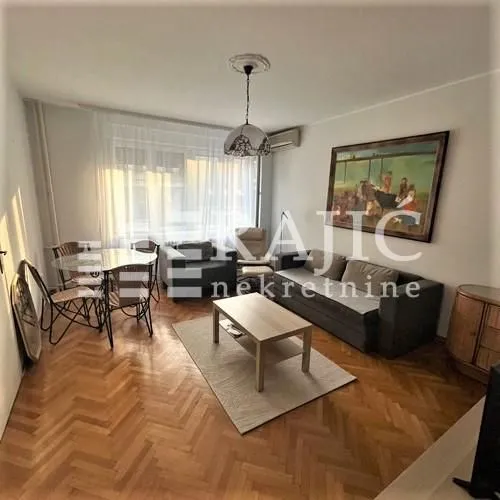 Living room with seating set, dining table and parquet flooring.