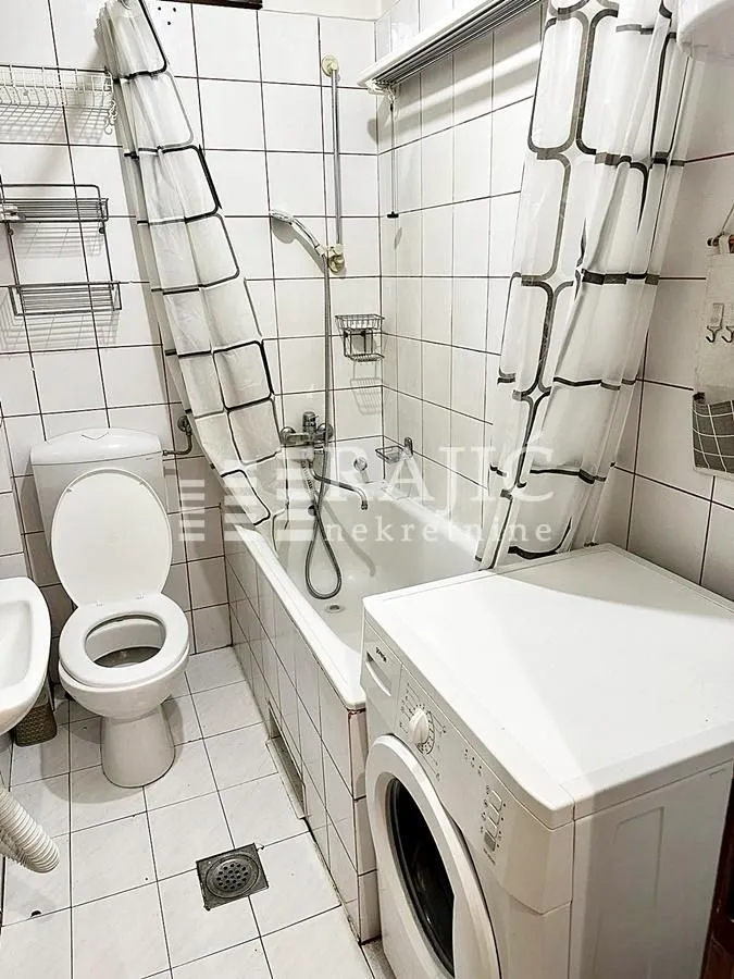 Smaller bathroom with a bathtub, toilet, and washing machine.