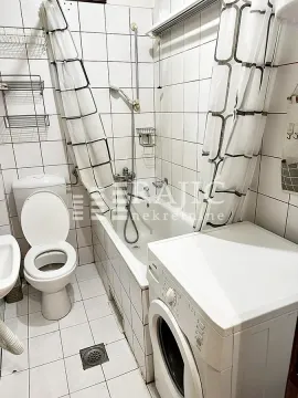 Smaller bathroom with a bathtub, toilet, and washing machine. - image 5