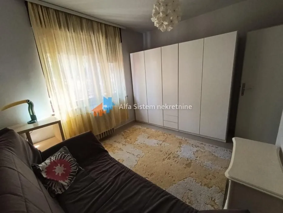 Furnished bedroom with a bed, large wardrobe, and window.