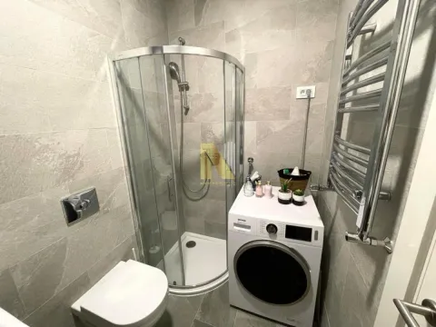 Modern bathroom with a shower enclosure, toilet, and washing machine. - image 7