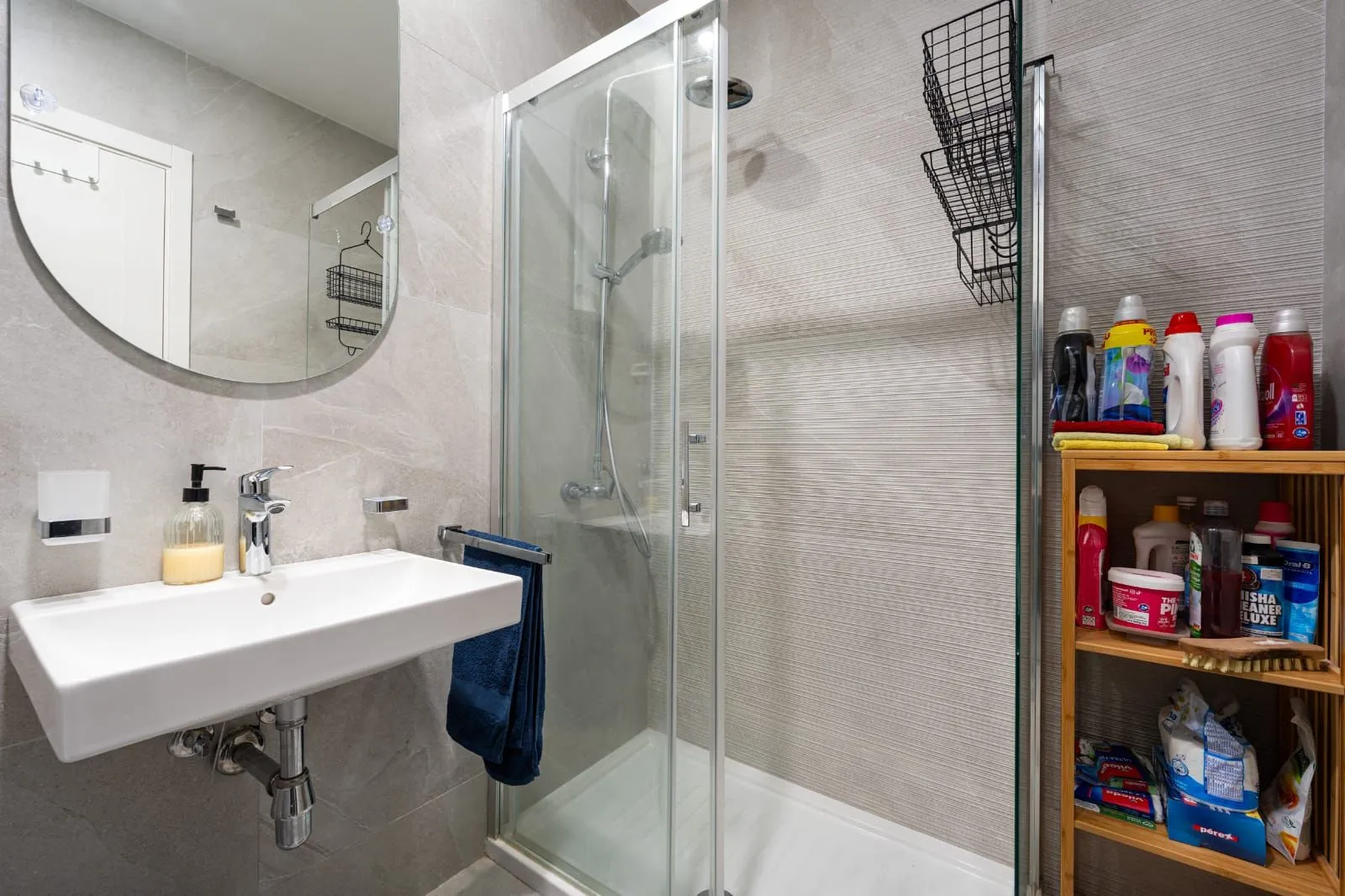 Modernly equipped bathroom with a shower cabin, washbasin, and mirror.