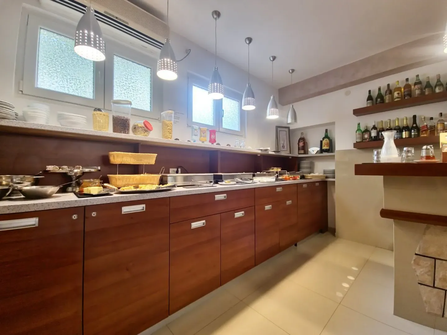 Kitchen with wooden cabinetry and hanging pendant lights.