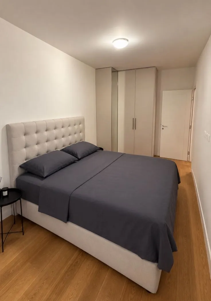 Moderna spavaća soba sa bračnim krevetom i ugradnim plakarom.