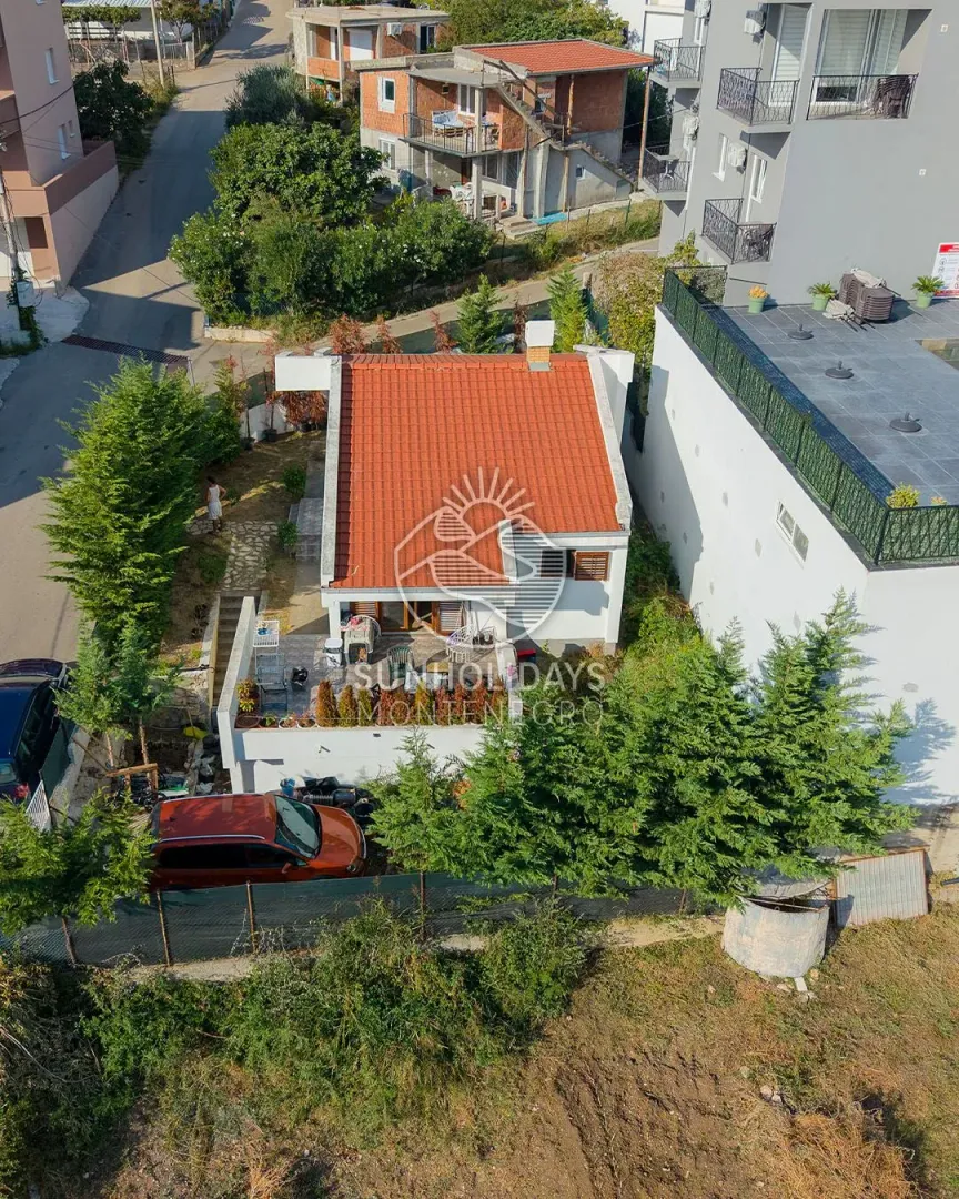 Pogled iz vazduha na kuću sa crvenim krovom i dvorištem.