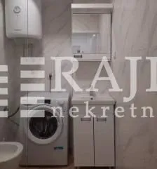 Small bathroom with a sink, washing machine, and water heater.