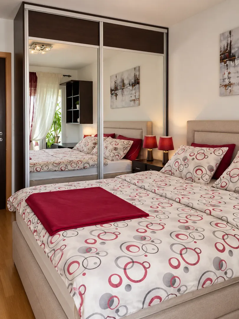 Furnished bedroom with a large double bed and a fitted wardrobe with mirror doors.