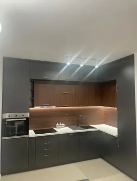 Modern kitchen with dark cabinets and built-in appliances. - image 3