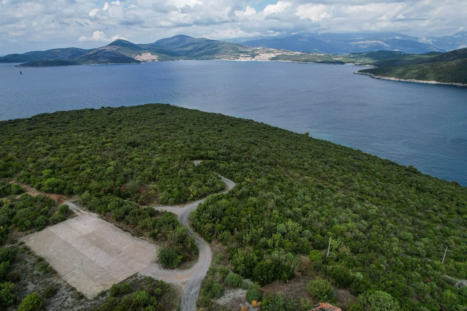 Pogled iz vazduha na šumoviti obalni pejzaž i more.