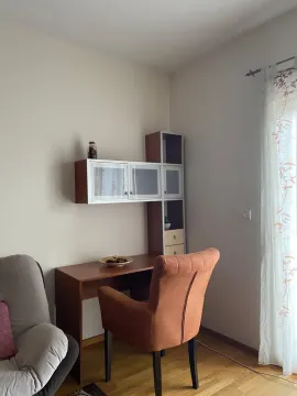 Radni kutak sa drvenim stolom, policama i narandžastom stolicom. - image 3