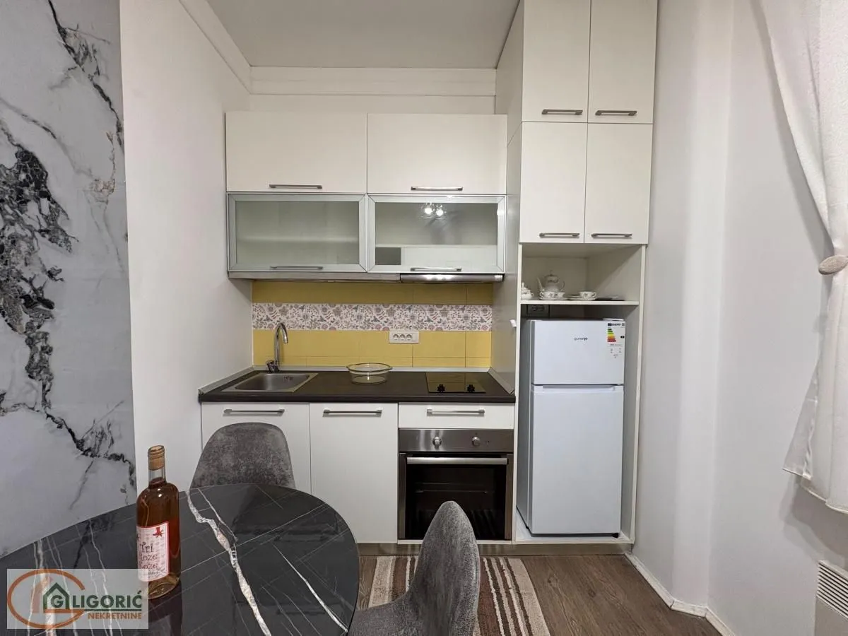 Small equipped kitchen with white cabinets and a refrigerator.