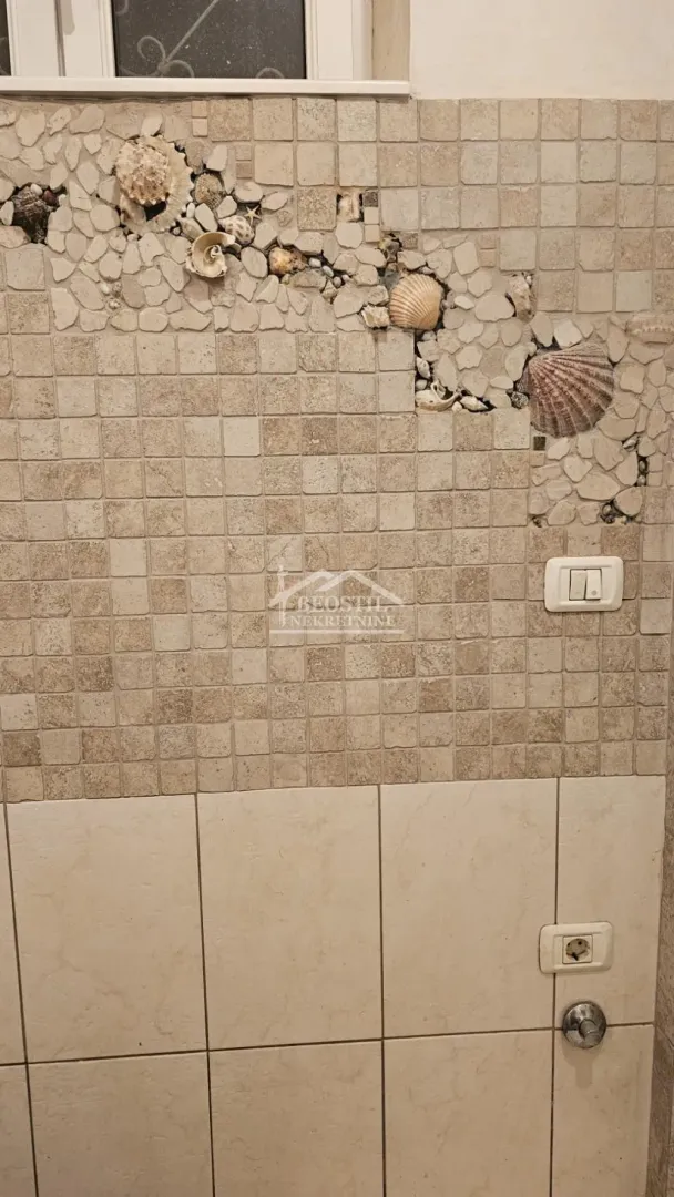 Detalj zida kupatila sa ukrasnim mozaikom od školjki i kamena.