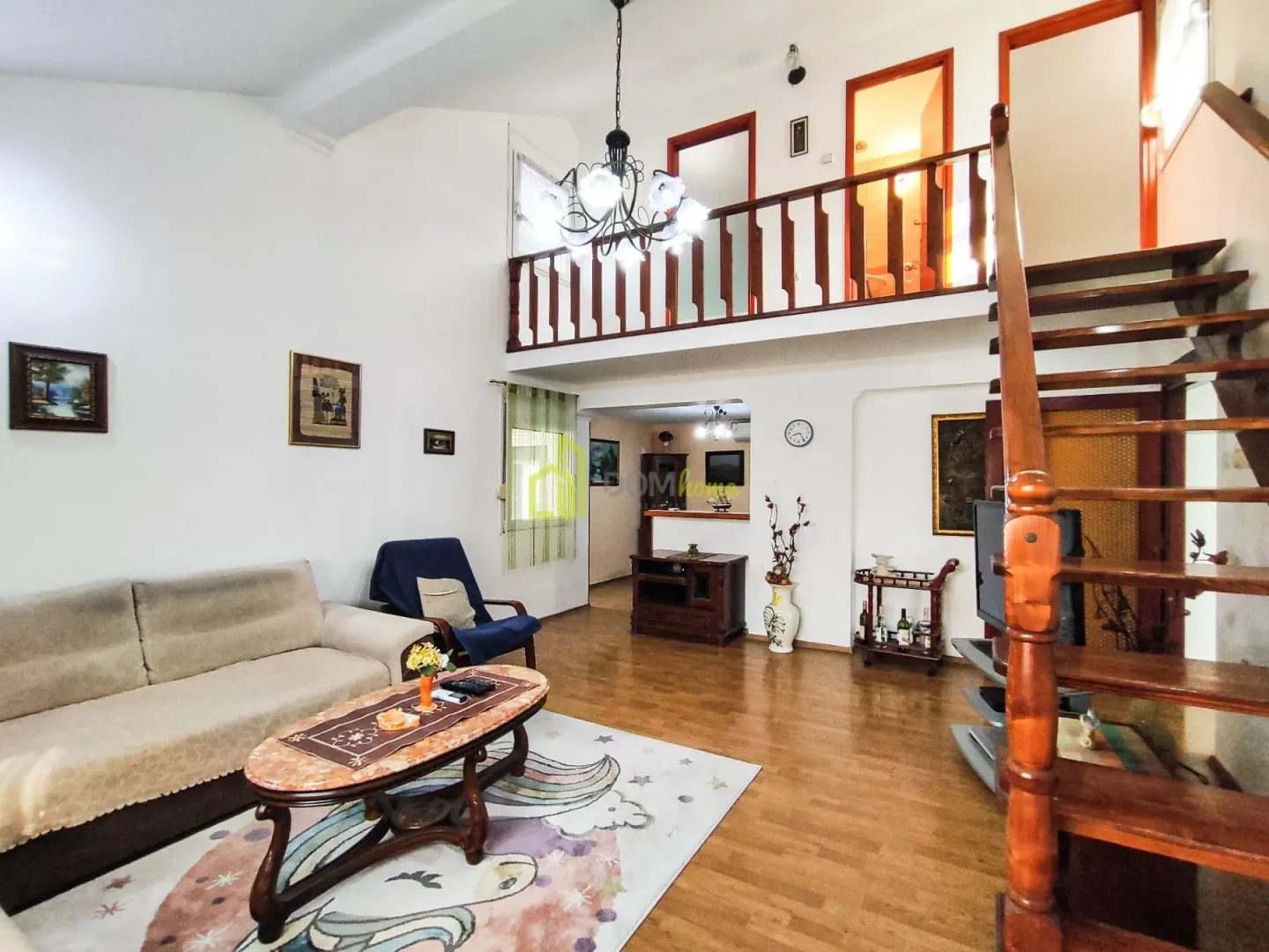 Living room with a sofa set, staircase and gallery on the upper floor.