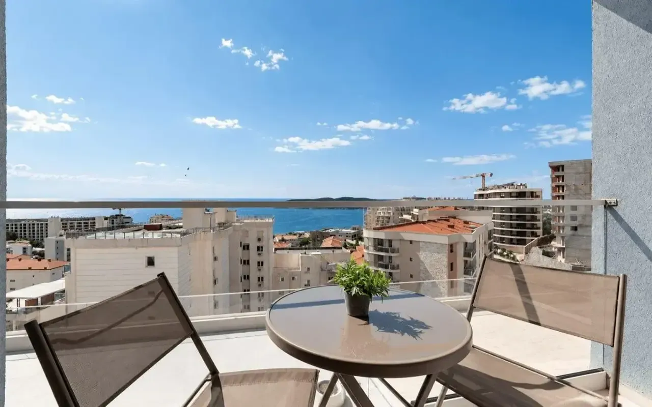 Namješten balkon sa pogledom na more i gradske zgrade.